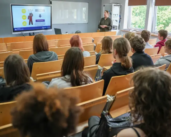 Wykład o przygotowaniu pedagogicznym dla psychologów. Studenci słuchają prelegentki przy tablicy interaktywnej.