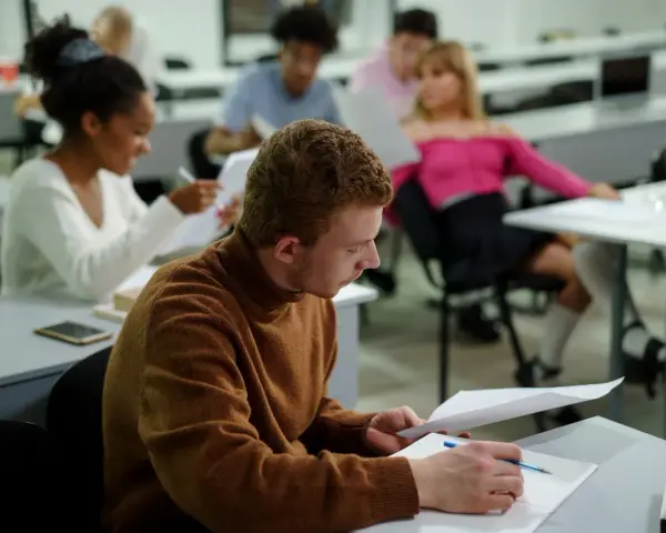 Studenci w sali wykładowej, skupieni na nauce. To dowód, że studia bez matury są możliwe i dają szansę na rozwój.