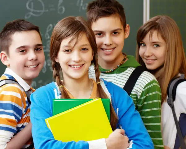 Uśmiechnięci uczniowie z podręcznikami, gotowi do nauki. Ich edukacja zdrowotna i program nauczania to klucz do przyszłości.