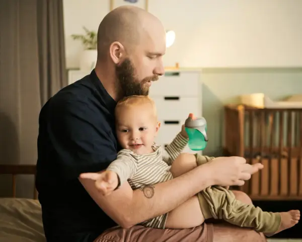 Ojciec z dzieckiem na rękach, czas spędzony razem to najlepszy urlop wychowawczy, lepszy niż urlop wypoczynkowy.