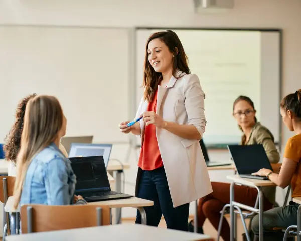 Nauczycielka wyjaśnia studentom, jak zostać nauczycielem, prowadząc lekcję w sali komputerowej.
