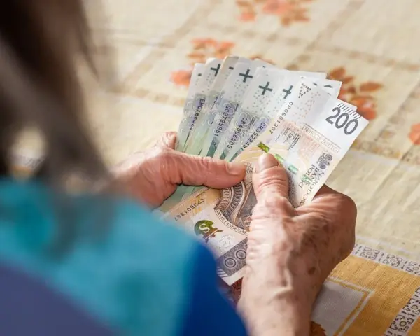 Dłonie liczą banknoty 200 zł. Zastanawiasz się, ile trzeba przepracować na 13 pensję?