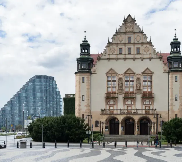 Imponujący budynek **Uniwersytetu im. Adama Mickiewicza w Poznaniu** obok nowoczesnego wieżowca.