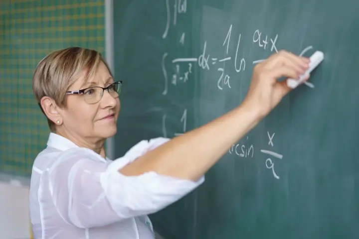 Nauczycielka matematyki pisze na tablicy wzory. Czy to zapowiedź podwyżki dla nauczycieli? Najnowsze wiadomości.