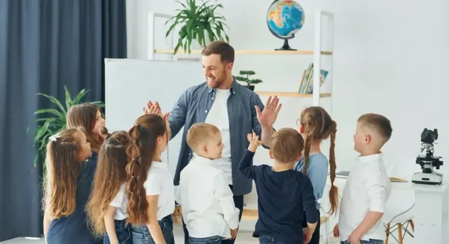 Nauczyciel z dziećmi świętuje koniec semestru. Wesoła klasa, która czeka na wystawienie ocen na 1 semestr.