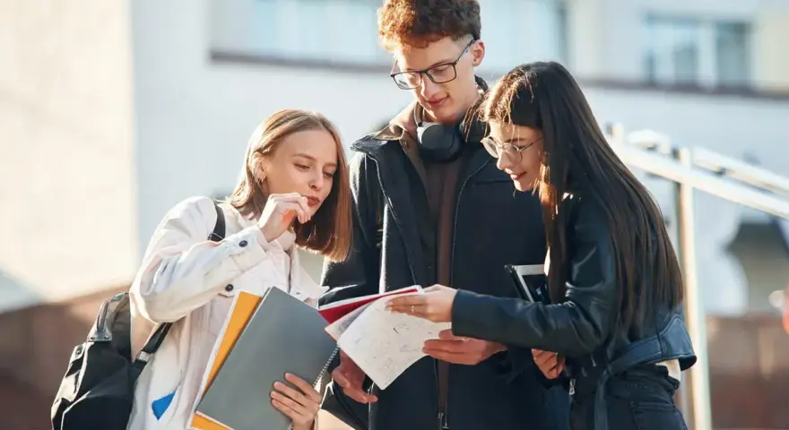 Trzech studentów dyskutuje o notatkach, zastanawiając się nad statusem ucznia a umową zlecenie.