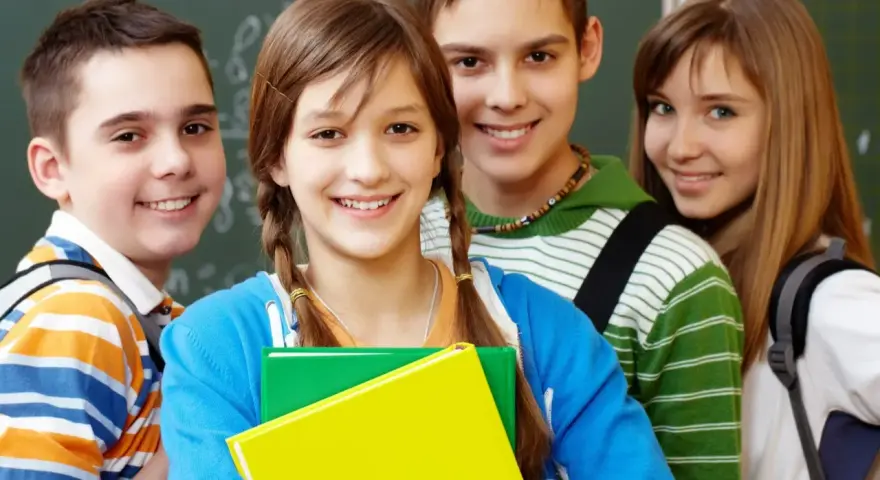 Uśmiechnięci uczniowie z podręcznikami, gotowi do nauki. Ich edukacja zdrowotna i program nauczania to klucz do przyszłości.