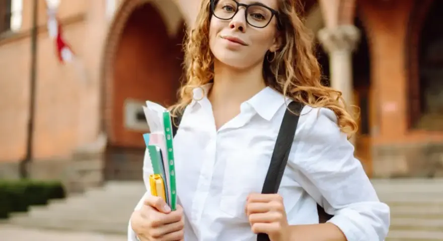 Studentka z okularami i zeszytami, gotowa do nauki. Jej klasyfikacja jako pilnej uczennicy jest oczywista.