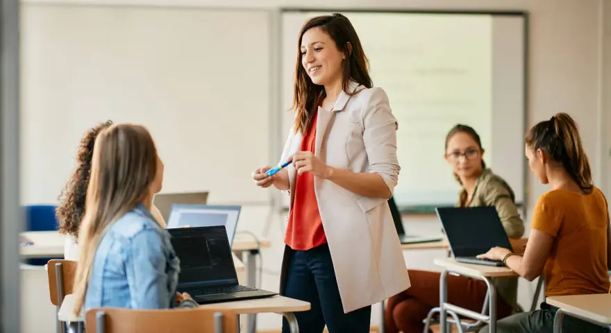 Nauczycielka wyjaśnia studentom, jak zostać nauczycielem, prowadząc lekcję w sali komputerowej.