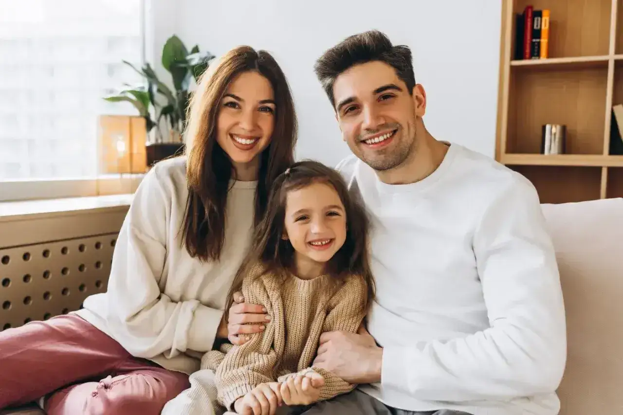 Szczęśliwa rodzina: mama, tata i córka uśmiechają się do aparatu. Idealna opieka na dziecko 2 dni w domu.
