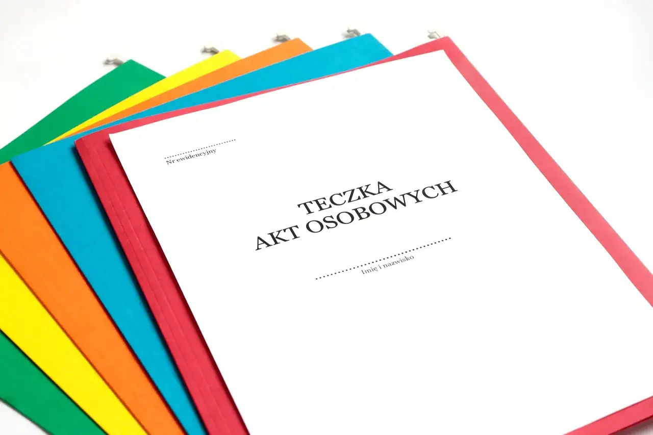 Kolorowe teczki z dokumentami, jedna z nich to Teczka Akt Osobowych, część A, gotowa do wypełnienia.