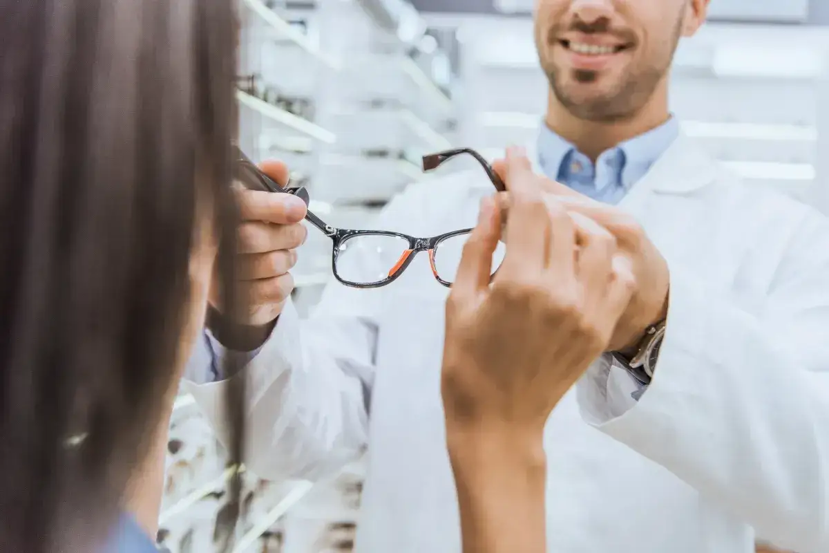 Okulista pokazuje klientce okulary. Dowiedz się, ile wynosi dofinansowanie do okularów przez pracodawcę.