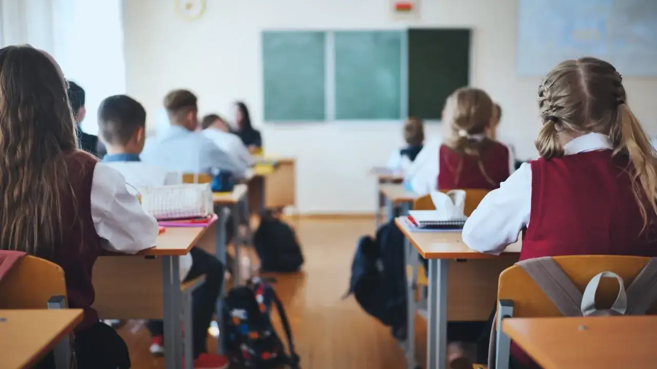Uczniowie siedzą w ławkach podczas hospitacji lekcji. W tle widać tablicę i nauczycielkę.