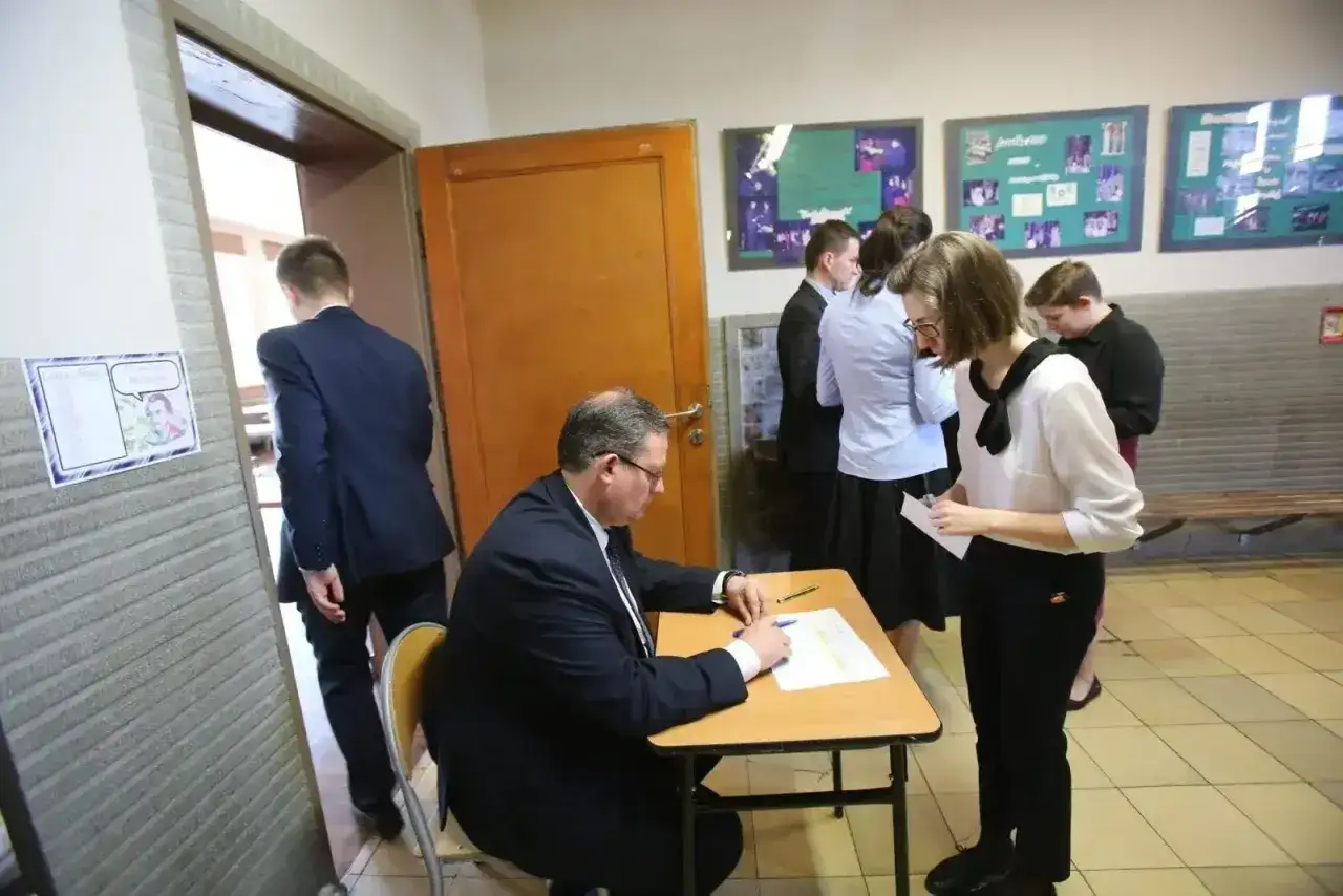 Napięcie przed matura ustna polski. Uczeń w garniturze wchodzi do sali, a przed egzaminatorem siedzi młoda dziewczyna.