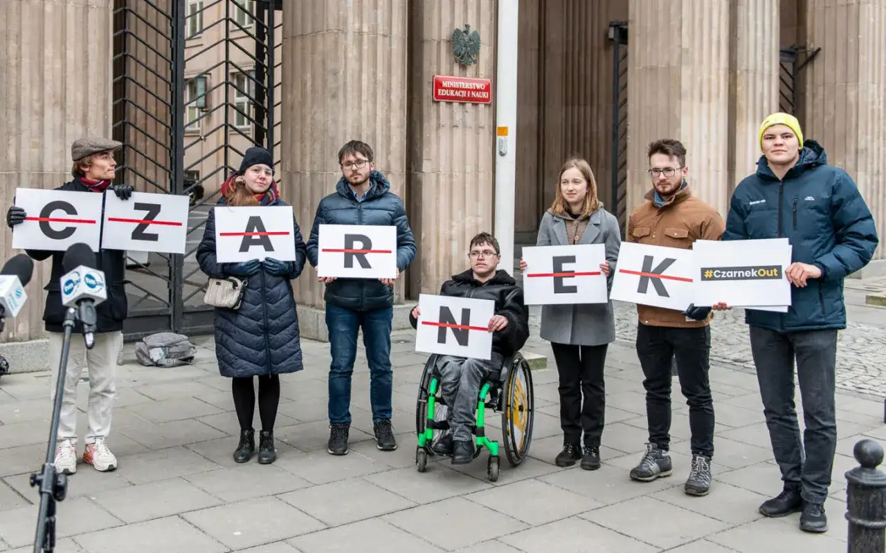 Protestujący przed Ministerstwem Edukacji i Nauki domagają się dymisji wiceministra edukacji, trzymając tabliczki z napisem