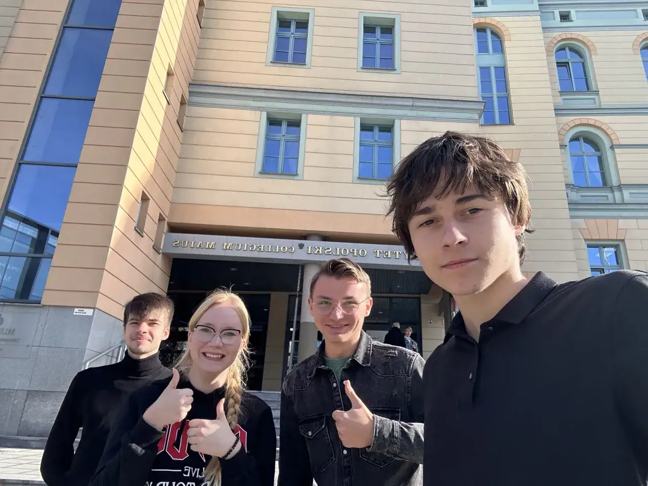 Czterech studentów przed budynkiem Collegium Polonicum, zadowoleni z zajęć z glottodydaktyki.